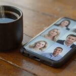 A smartphone and steaming coffee cup on a wooden table